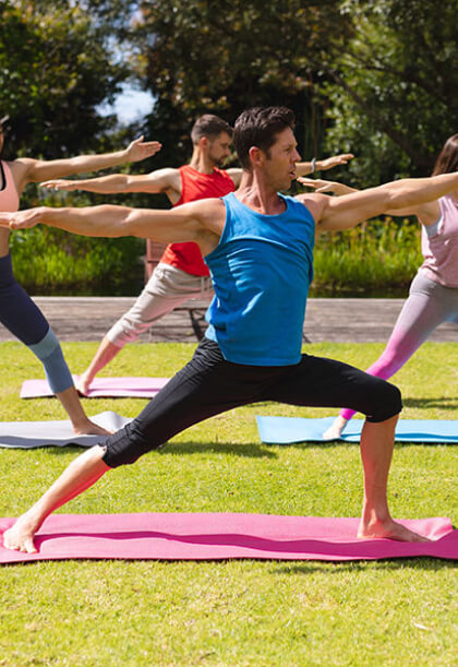 Man performing warrior tai-chi pose outdoors on grass